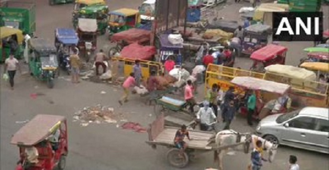 दिल्ली की आजादपुर फल और सब्जी मंडी के बाहर लोग खरीदारी कर सामान ले जाते हुए
